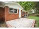 View of the brick home's backyard, featuring a concrete patio and manicured lawn at 4921 Churchill Dr, Charlotte, NC 28269