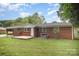 A wide shot of the backyard and brick house, showing the patio, air conditioning unit and fenced in yard at 4921 Churchill Dr, Charlotte, NC 28269