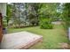 A partial view of the concrete patio and a backyard with mature trees and landscaped areas at 4921 Churchill Dr, Charlotte, NC 28269