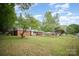 Landscaped front yard of a brick home featuring mature trees and a well-manicured lawn at 4921 Churchill Dr, Charlotte, NC 28269