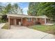 Exterior view of the brick home featuring a carport and covered entryway, plus a concrete patio in the backyard at 4921 Churchill Dr, Charlotte, NC 28269