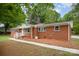 Side view of a brick house with white trim, a walkway, and mature trees at 4921 Churchill Dr, Charlotte, NC 28269