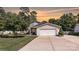 Charming exterior view featuring a well-manicured lawn, lush greenery, and a two-car garage at 7018 Huntsmaster Dr, Charlotte, NC 28277