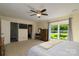 This main bedroom features a ceiling fan, carpet, and a window overlooking the front yard at 7018 Huntsmaster Dr, Charlotte, NC 28277