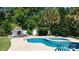 Sparkling pool with adjacent fireplace and lush landscaping creating a private backyard oasis at 7018 Huntsmaster Dr, Charlotte, NC 28277