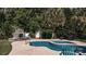 Backyard pool area featuring an outdoor fireplace, stone surround, and lush landscaping at 7018 Huntsmaster Dr, Charlotte, NC 28277