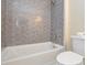 Close-up of dark subway tile shower, toilet, and tub in updated bathroom at 9713 Autumn Applause Dr, Charlotte, NC 28277