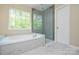 Spa-like bathroom featuring a soaking tub, a walk-in shower, and a large window offering serene outdoor views at 9713 Autumn Applause Dr, Charlotte, NC 28277