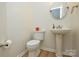 Clean half bathroom with pedestal sink, toilet, and neutral decor at 9713 Autumn Applause Dr, Charlotte, NC 28277