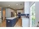 Bright kitchen with white cabinets, blue backsplash, stainless steel appliances, and large center island at 9713 Autumn Applause Dr, Charlotte, NC 28277