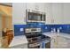 Modern kitchen featuring stainless steel appliances, white cabinets, and a stylish blue backsplash at 9713 Autumn Applause Dr, Charlotte, NC 28277