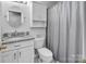 Bright bathroom featuring a granite countertop, round mirror, and shower with a neutral-colored curtain at 1002 Banaba Dr, Indian Trail, NC 28079