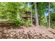 View of a home through the trees with a wooden porch and overgrown foliage at 11024 Hunters Trace None, Charlotte, NC 28262
