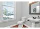 Well-lit powder room features a pedestal sink, mirror, and large window for natural light at 1105 Hoyle Ln, Waxhaw, NC 28173