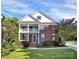 Charming two-story brick home with a covered front porch and lush landscaping under a bright blue sky at 1105 Hoyle Ln, Waxhaw, NC 28173
