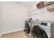 Well-equipped laundry room with modern washer and dryer, wire shelving, and tile flooring at 1105 Hoyle Ln, Waxhaw, NC 28173