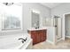Bright main bathroom has a soaking tub, glass shower, and a vanity with dark cabinets at 1105 Hoyle Ln, Waxhaw, NC 28173