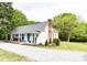 Beautiful exterior view of home with rocking chairs on the porch, a brick chimney, and a lush, landscaped yard with scattered trees at 1165 Old Salisbury Concord Rd, Concord, NC 28025