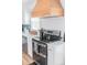 Stove close-up with stainless steel appliances, white cabinetry, and a wood vent hood, enhanced by wood flooring at 1165 Old Salisbury Concord Rd, Concord, NC 28025