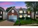 Beautiful brick home with bright blue shutters, a well-manicured lawn, and attached two-car garage at dusk at 12404 Mcallister Park Dr, Charlotte, NC 28277