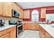 Well-equipped kitchen featuring wood cabinets, stainless steel appliances, and arched window above the sink at 2003 Dataw Ln, Indian Trail, NC 28079