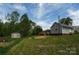 Side view of a home featuring a large backyard, storage shed, and small wood porch at 2019 Kingston Rd, Kingstown, NC 28150