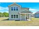 View of the house's back exterior with bright lawn and covered patio with grill at 207 Aspire Cir # 46, Wingate, NC 28174