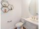 Stylish powder room with a pedestal sink, round mirror, and decorative shelves for storage at 2558 Deacon Ave, Charlotte, NC 28204