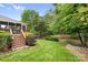 Lush backyard featuring a patio, wooden deck, mature trees, and privacy landscaping at 2710 Providence Spring Ln, Charlotte, NC 28270