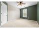 Empty bedroom with neutral carpet, olive accent wall, and a window with plantation shutters at 2710 Providence Spring Ln, Charlotte, NC 28270
