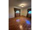 Bedroom featuring hardwood floors, warm neutral walls, and two windows with decorative curtains at 28344 Canton Rd, Albemarle, NC 28001