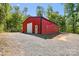 Exterior view of a large red barn with a gravel driveway surrounded by lush trees at 29268 Pennington Rd, Albemarle, NC 28001
