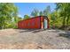 Exterior view of a large red barn with a gravel driveway, nestled among mature trees at 29268 Pennington Rd, Albemarle, NC 28001