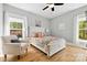 Cozy bedroom features a white bed frame, wood floors, and natural light from two windows at 29268 Pennington Rd, Albemarle, NC 28001