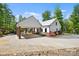 Exterior showcasing a white farmhouse with a covered carport featuring brick columns and manicured landscaping at 29268 Pennington Rd, Albemarle, NC 28001