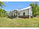 A side view of a modern farmhouse featuring white siding, dark-framed windows, and a large covered porch at 29268 Pennington Rd, Albemarle, NC 28001