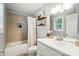 Cozy bathroom featuring a shower-tub combo and shelving with decorative items at 303 Caroline Ave, Lowell, NC 28098