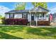 Charming home with a well-manicured lawn and a cozy front porch decorated with flowering bushes and an American flag at 303 Caroline Ave, Lowell, NC 28098