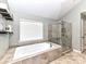 Relaxing bathroom featuring a soaking tub, a glass-enclosed shower, and neutral tiling at 3057 Drummond Ave, Indian Land, SC 29707