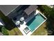 Aerial view of a backyard pool and jacuzzi with patio, umbrellas, and lounge seating at 3057 Drummond Ave, Indian Land, SC 29707