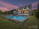 Evening view of a backyard pool area with spacious patio and screened in porch at 3057 Drummond Ave, Indian Land, SC 29707