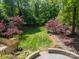 Lush backyard shows mature trees, green grass, stone patio, and privacy fencing at 3233 Sunnymede Ln, Charlotte, NC 28209