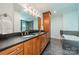 Elegant bathroom with double vanity, sleek mirrors, wood cabinets, a soaking tub, and glass-enclosed shower at 3233 Sunnymede Ln, Charlotte, NC 28209