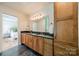 Spacious bathroom with double vanity, wood cabinets, a large mirror, and bedroom access at 3233 Sunnymede Ln, Charlotte, NC 28209