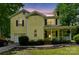 Charming two-story yellow home featuring a covered front porch and attached garage, with evening lighting at 3619 Baywoods Ct, Gastonia, NC 28056