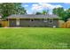 Gray brick house features a grassy backyard and a white back door at 4009 Dunwoody Dr, Charlotte, NC 28215