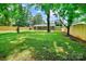 Large backyard with a green lawn, mature trees, and a wooden fence at 4009 Dunwoody Dr, Charlotte, NC 28215