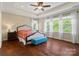 Sunlit bedroom featuring hardwood floors, tray ceiling, bench, and large windows overlooking the trees at 5301 Meadowcroft Way, Fort Mill, SC 29708