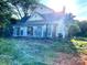 View of a two-story home with a sunroom surrounded by overgrown greenery at 6000 S Main St, Salisbury, NC 28147