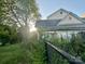 Two-story home with sunroom on overgrown lot with a dark fence in foreground at 6000 S Main St, Salisbury, NC 28147